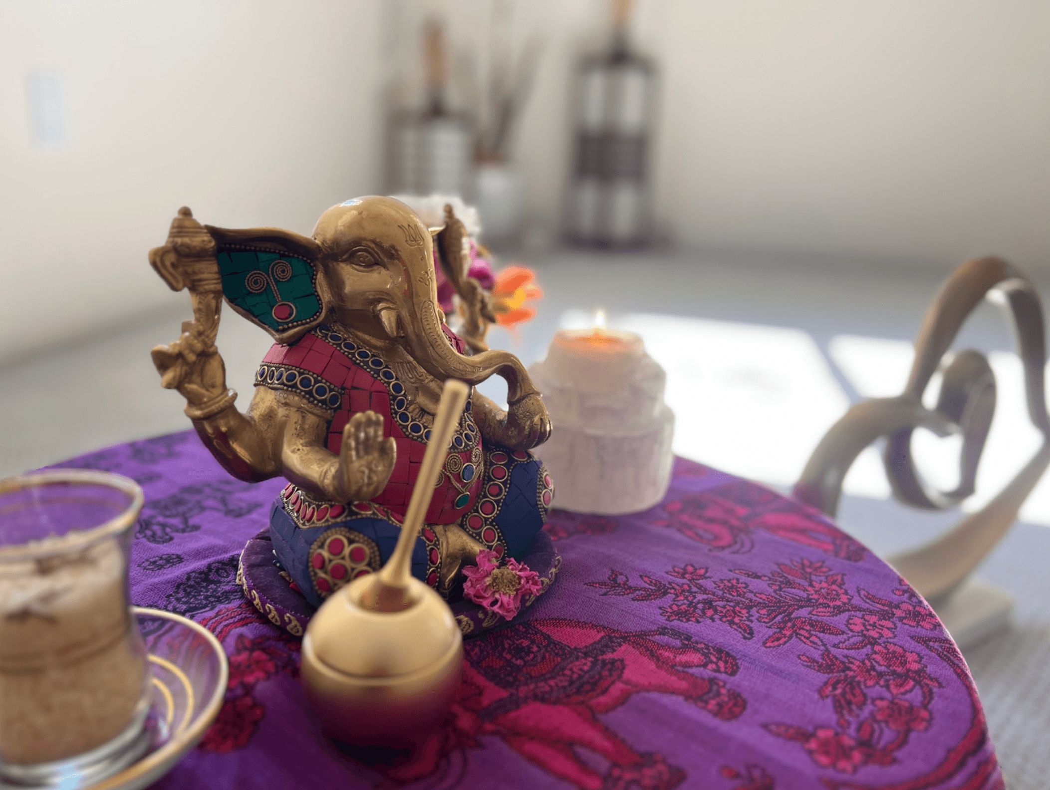 A small brass Ganesh statue and candle resting on a ceremony table inside Sicatuva
