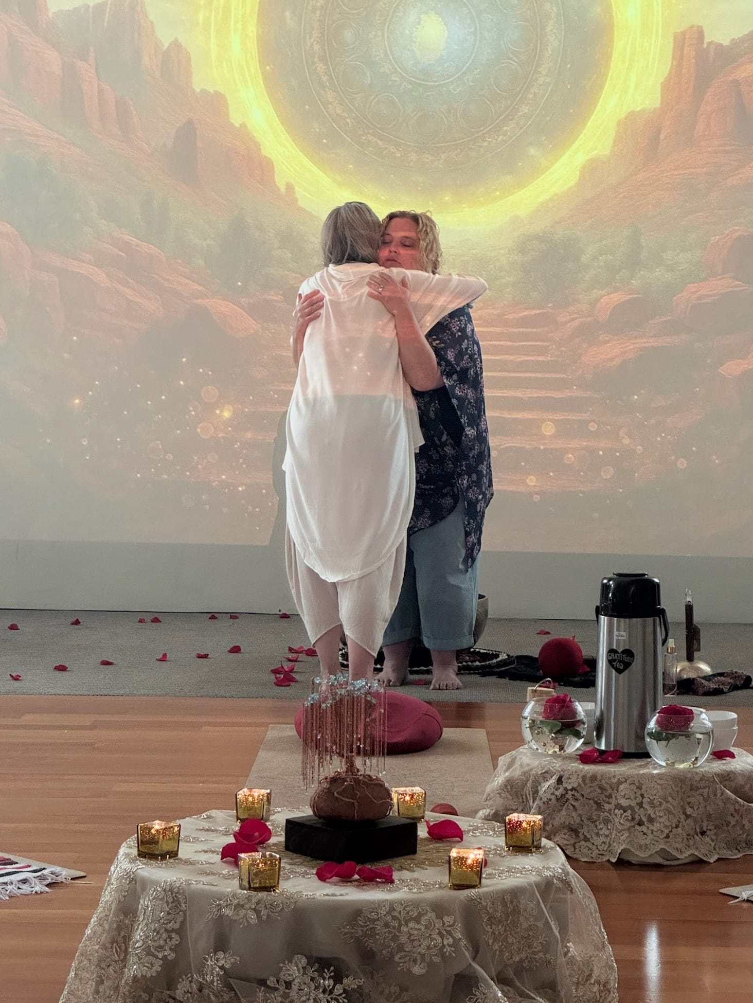 Two guests sharing a heartfelt embrace before the altar at the close of a ceremony, held gently by the team