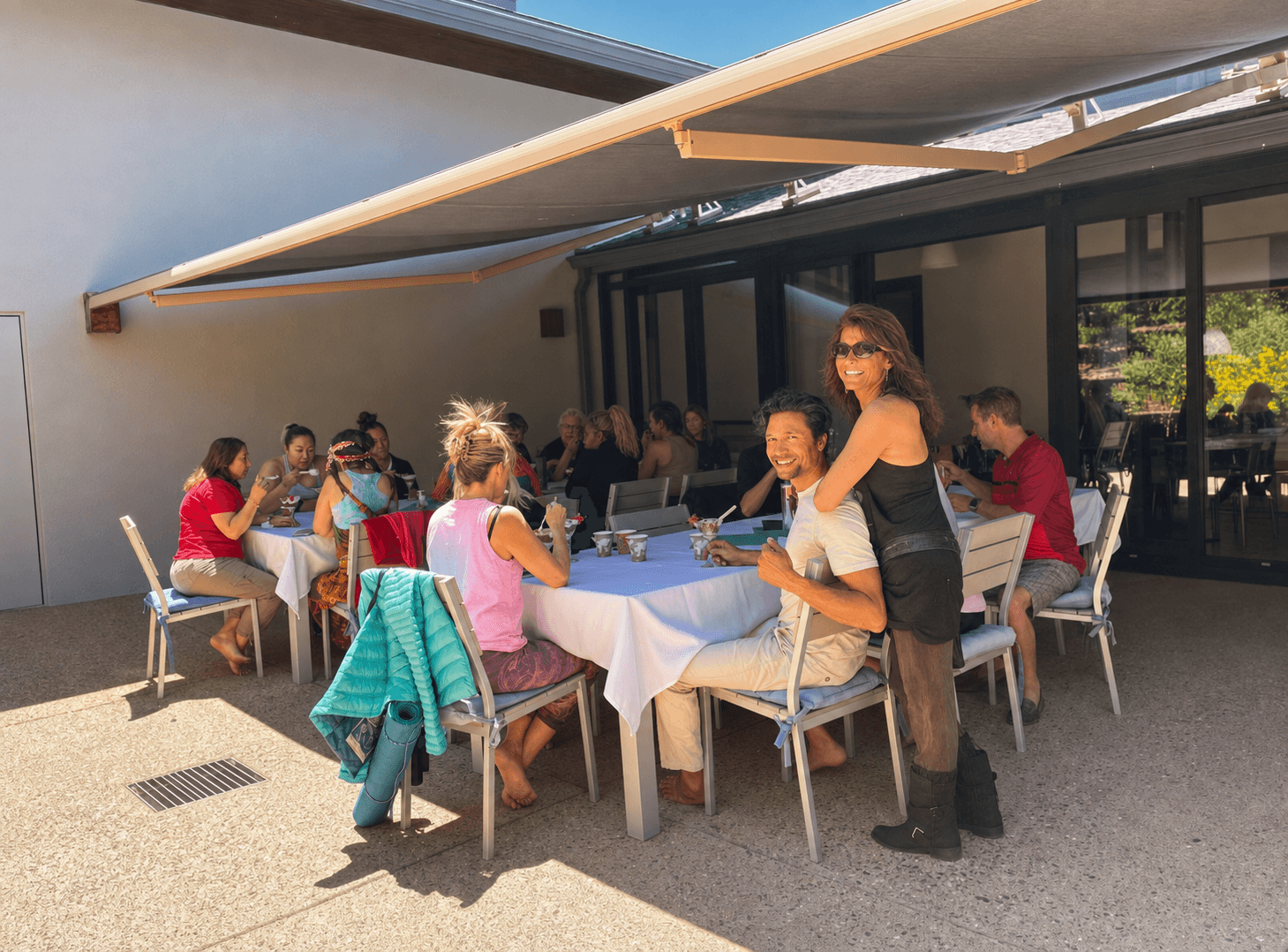 Retreat guests linger over conversation beneath the awning, the day's schedule opening into unhurried time together